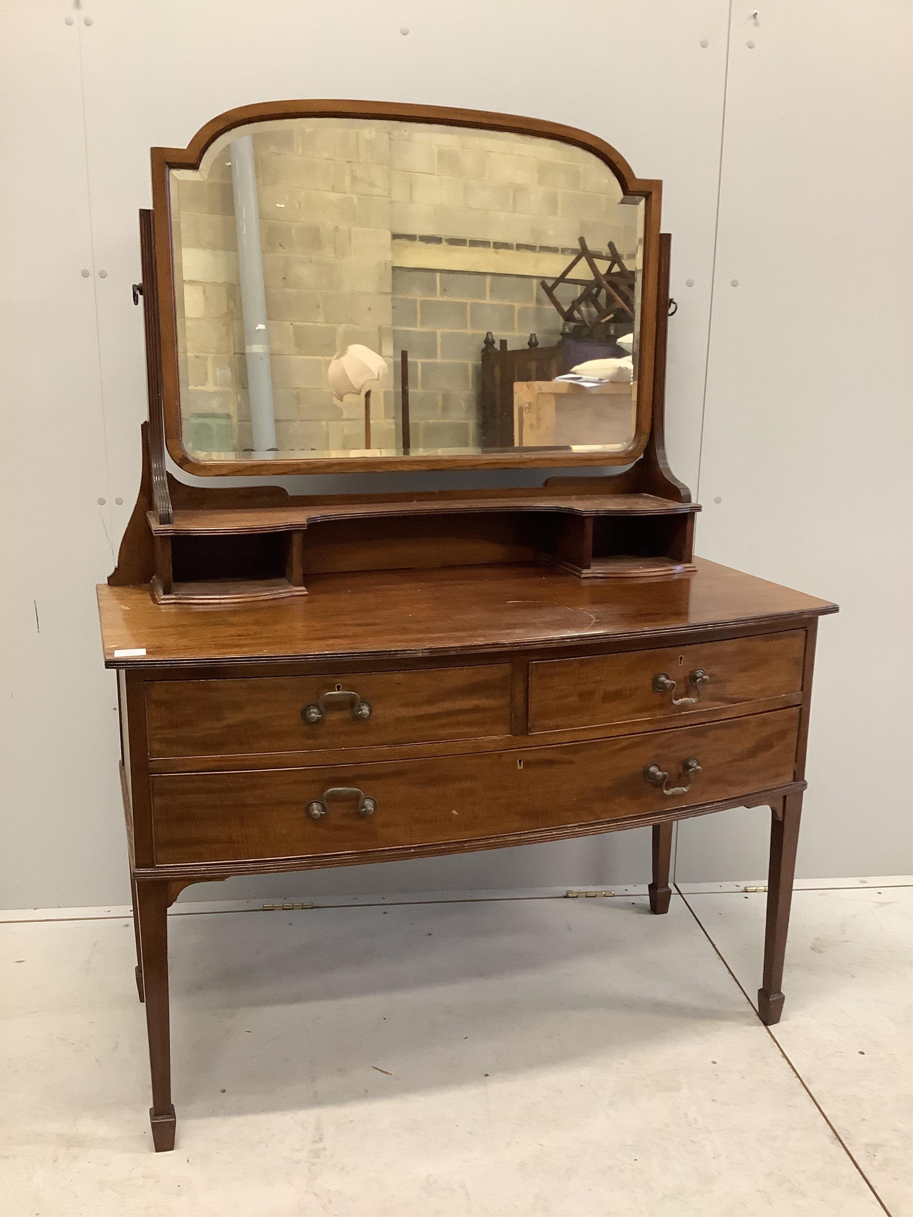 An early 20th century mahogany bowfront dressing table, fitted two short and one long drawer with brass loop handles and square tapered legs with spade feet, width 116cm, depth 57cm, height 156cm. Condition - fair